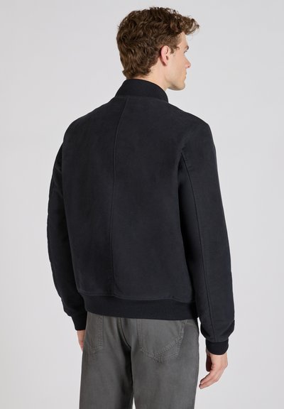 Zwarte bomberjack gemaakt van zachte stof, met een geribde kraag en manchetten, en een schone, minimalistische uitstraling zonder zichtbaar merk.