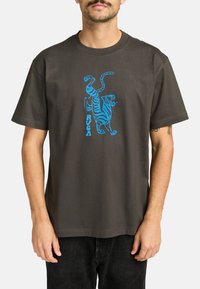 Heren T-shirt van katoen in houtskoolkleur met een blauwe grafische afbeelding van een tijger en de tekst "RUGA" op de voorkant. Korte mouwen en een ontspannen pasvorm.