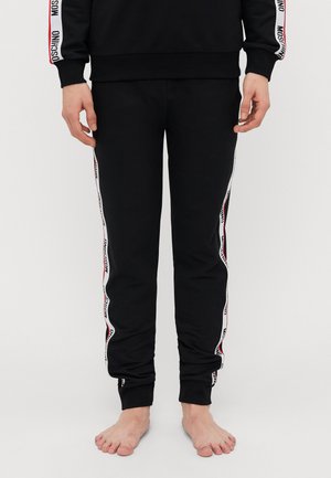 Black sweatpants made of cotton blend, featuring white and red side stripes with text, elastic waistband, and ribbed cuffs.