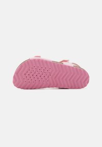 Rosa gummisåle med en sikksakk-mønster, med ventilasjonsåpninger. Designet med justerbare stropper for sikker passform.