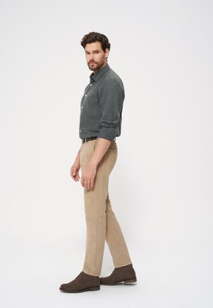 Szara koszula z długim rękawem, beżowe spodnie i brązowe zamszowe buty. Koszula ma kieszeń na piersi, a spodnie mają dopasowany krój z teksturowym wykończeniem.