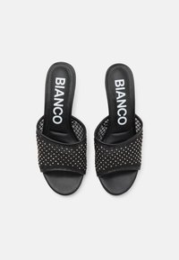 Chanclas negras con un diseño texturizado y con tachuelas, con una parte superior de malla. La plantilla tiene un acabado suave y muestra el logotipo "BIANCO".