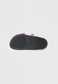 Suola di sandalo rosa slip-on con tamponi in gomma nera testurizzata sul tallone e sulle aree del pallone, isolata su sfondo bianco.