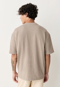 T-shirt met korte mouwen en losse pasvorm in lichtbruin gestructureerd stof, met een eenvoudige ronde hals en zonder zichtbare patronen of accenten.