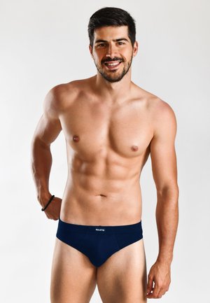 Navy blue men's briefs with a soft fabric, elastic waistband, and front seam detailing, worn by a model with a bare upper body.