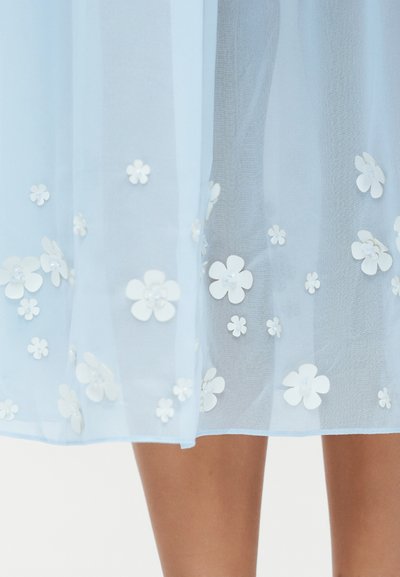 Fustă albastru deschis transparentă cu aplicații florale tridimensionale albe, prezentată de la jumătatea coapsei până sub genunchi.
