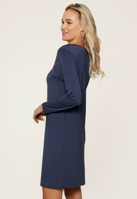 Robe bleu marine à manches longues avec un col rond, en tissu doux, coupe décontractée et longueur jusqu'aux genoux. Présente une texture lisse et des détails minimalistes.
