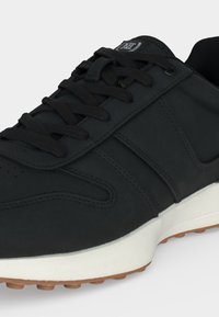 Μαύρο sneaker χαμηλού τύπου με μαύρα κορδόνια, ραφές, λευκή ενδιάμεση σόλα και λαστιχένια εξωτερική σόλα με πέλματα για καλύτερη πρόσφυση.