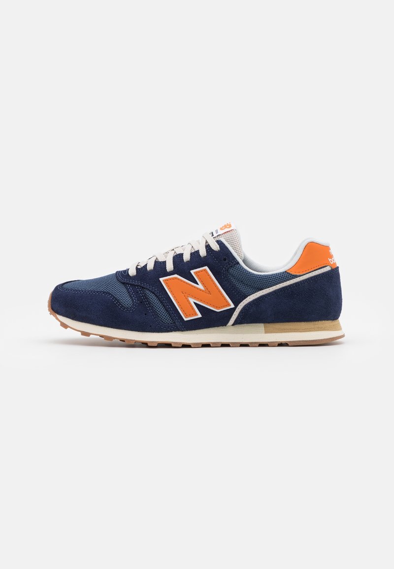 Baskets New Balance bleu marine et orange avec lacets blancs, dessus en mesh et en daim, et semelle en caoutchouc, vues de profil sur fond blanc.