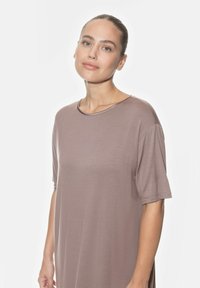 Robe courte mauve clair à manches courtes, avec un col rond et une coupe décontractée, réalisée dans un tissu doux et texturé. Fentes latérales visibles.