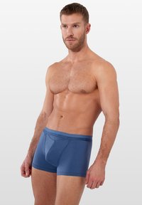 Pánské modré boxery z měkké látky s hladkým zakončením, přiléhavým střihem a vyraženým logem na pásku.