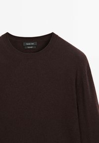 Maglione in cashmere marrone scuro con scollatura rotonda e maniche lunghe. Il tessuto è morbido, liscio e presenta un'etichetta con il marchio Massimo Dutti.