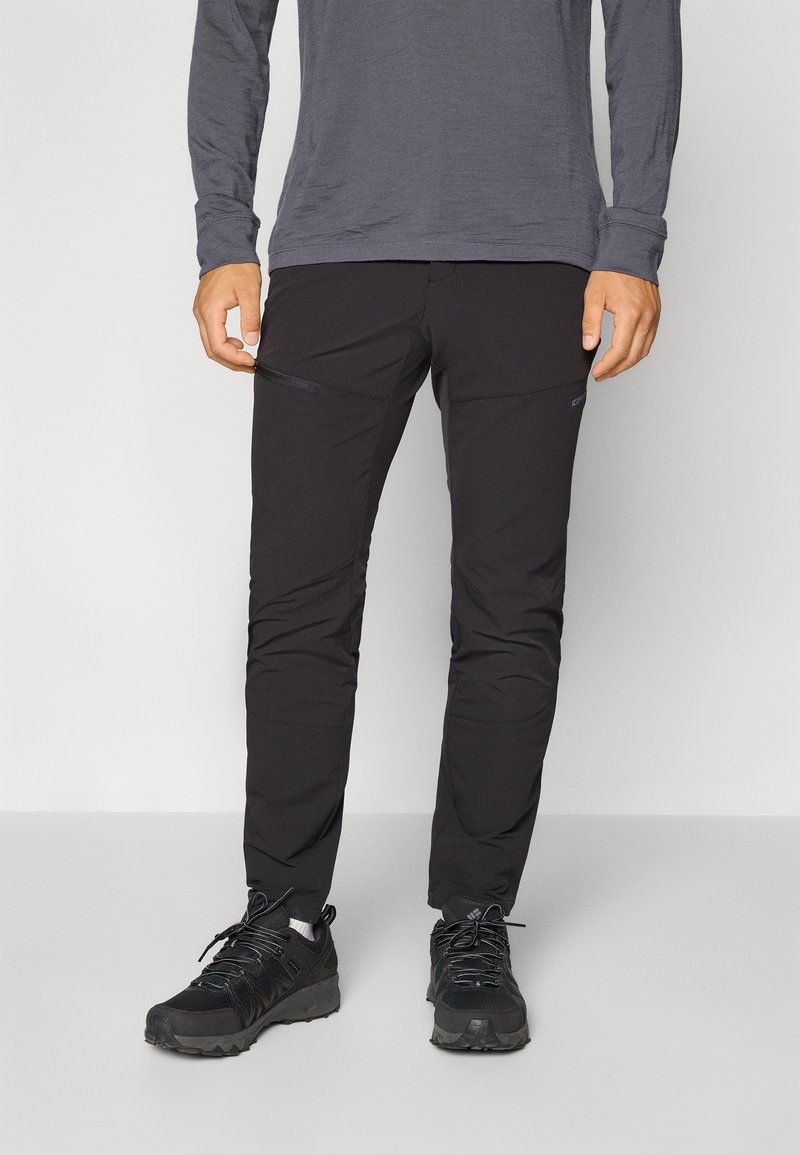 Zwarte outdoorbroek met ritszakken, gemaakt van een lichtgewicht, flexibele stof. Gekocht met zwarte wandelschoenen. Grijze top met lange mouwen.