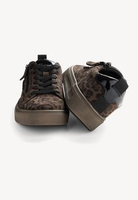 Baskets à imprimé léopard avec lacets noirs, tissu texturé et un accent de talon brillant noir contrastant. Elles possèdent une semelle rembourrée et une fermeture éclair.