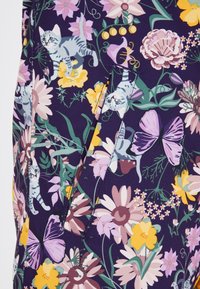 Bloemig kledingstuk met een donkerpaarse achtergrond. De patronen bevatten katten en verschillende bloemen in tinten van roze, geel en groen met een gladde textuur.