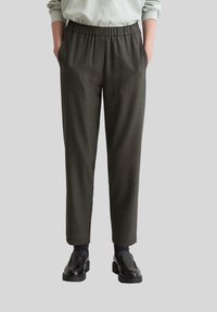 Pantalons gris fuselés en tissu texturé, dotés d'une taille élastique et de poches latérales, associés à des chaussures noires.