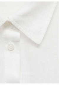 Col blanc en lin avec fermeture à bouton. Le tissu a une texture subtile, et le col est pointu avec des coutures soignées.