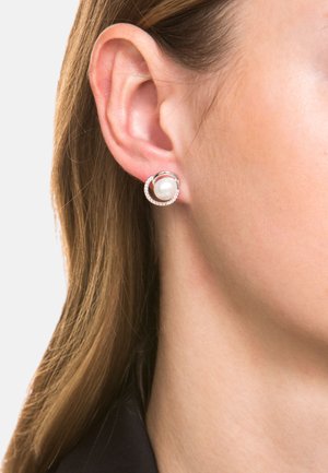 Orecchini in argento con una perla bianca tonda al centro, circondata da una fascia circolare decorata con piccole pietre trasparenti.