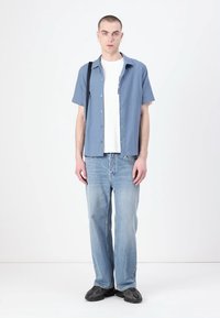 Short-sleeve, light blue checkered shirt, white t-shirt underneath, paired with light blue jeans and black sneakers. Simple design and casual fit.