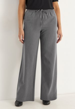 Grijze wijde broek met een elastische tailleband en koord, gemaakt van een zachte, gestructureerde stof, gecombineerd met zwarte schoenen.