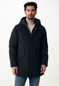 Černá péřová bunda s kapuc í, vybavená dvěma náprsními kapsami, bočními kapsami a zipovým zapínáním. Stylizováno přes světle béžový rolák.