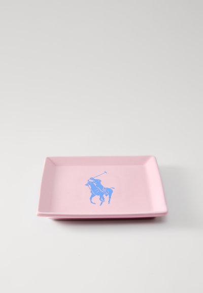 Négyzet alakú, rózsaszín kerámia tányér, közepén egy kék polo játékost ábrázoló grafikával. Simább felület enyhén kiemelkedő szegélyekkel.