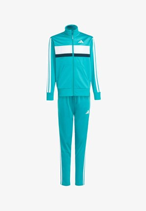 Turkoosi treenipuku valkoisilla ja tummansinisillä raidoilla, vetoketjullinen takki, kaksi taskua ja samansuuntaiset kapenevat housut, joissa on valkoinen Adidas-logo.
