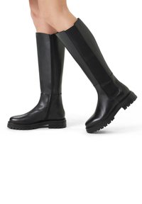 Black knee-high boots made of smooth leather with a textured elastic panel, a rounded toe, and a rugged sole for traction.