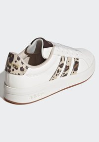 Bijela tenisica s leopard uzorkom na peti i sa strane. Gornji dio od glatke kože, vezanje na vezice, podstavljeni ovratnik i gumeni potplat.