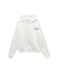 Weiße Reißverschlussjacke aus weichem Stoff mit einer Fronttasche. Mit rotem Text: "ICH BIN KEINE PRINZESSIN, ICH BIN DIE KÖNIGIN!" auf der linken Brust.