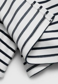 Tessuto di maglia in cotone bianco con righe blu navy, caratterizzato da una superficie liscia e cuciture scure a contrasto lungo i bordi.