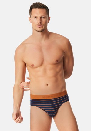Herren-Slip in Marineblau mit orangenen Streifen und einem Logo am Bund. Der Stoff wirkt weich und das Design enganliegend.