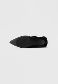 Black pointed-toe high heel shoe shown from the sole with textured grip on a plain white background.