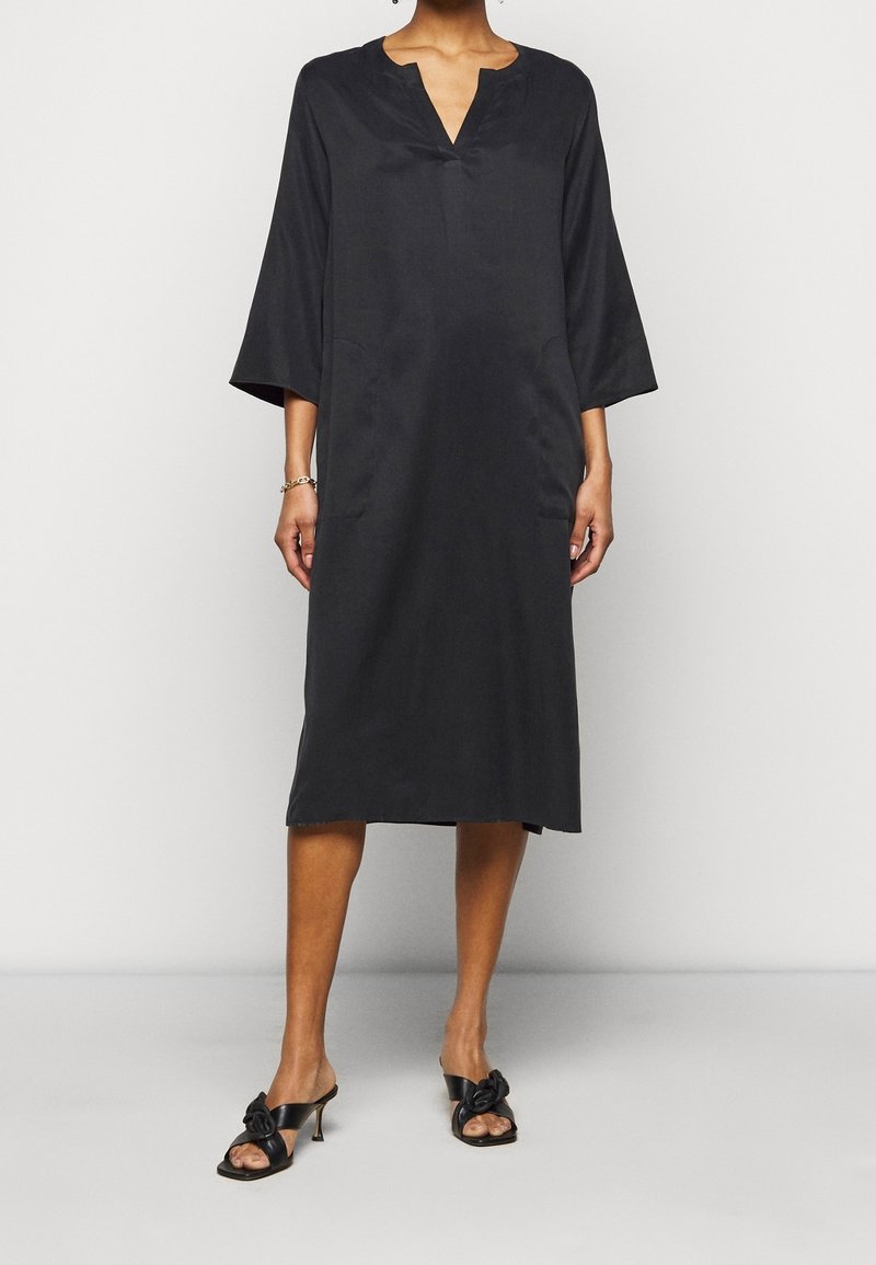 Mustahdud pugat musta knee-length, na Gbanwi o iru ise, ndu ogbu, na ogbu. Amaka na etu, n'echiche nke ndi kachasi elu, kwadoro na sandals heeled mmanwu ojii.