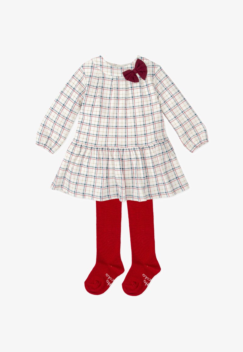 Vestido a cuadros en crema, azul y rojo con mangas largas, cintura fruncida y lazo burdeos; combinado con medias rojas hasta la rodilla.