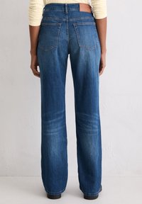 Niebieskie dżinsy z wysokim stanem, proste nogawki i wzór z pięcioma kieszeniami. Na tylnej części pasa naszywka z brązowej skóry z logo marki.