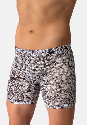 Männlicher Oberkörper, der eng anliegende Boxershorts mit einem schwarzen, weißen und grauen abstrakten Muster vor einem einfarbigen Hintergrund trägt.