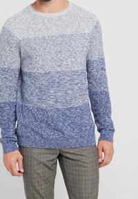 Gestrickter Pullover mit Farbverlauf von Hellgrau zu Dunkelblau. Rundhalsausschnitt, lange Ärmel und gerippte Bündchen mit strukturiertem Muster.