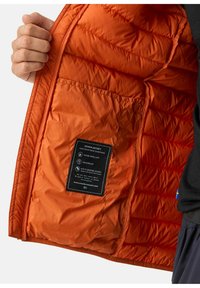 Oranje donsjas met een interieur dat een gestikte textuur heeft, waterafstotende en winddichte eigenschappen, met een zwart verzorgingslabel en zak.