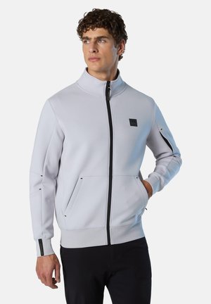 Giacca zip grigia chiara con collo alto, due tasche frontali, dettagli neri e logo. Realizzata in materiale morbido e testurizzato.