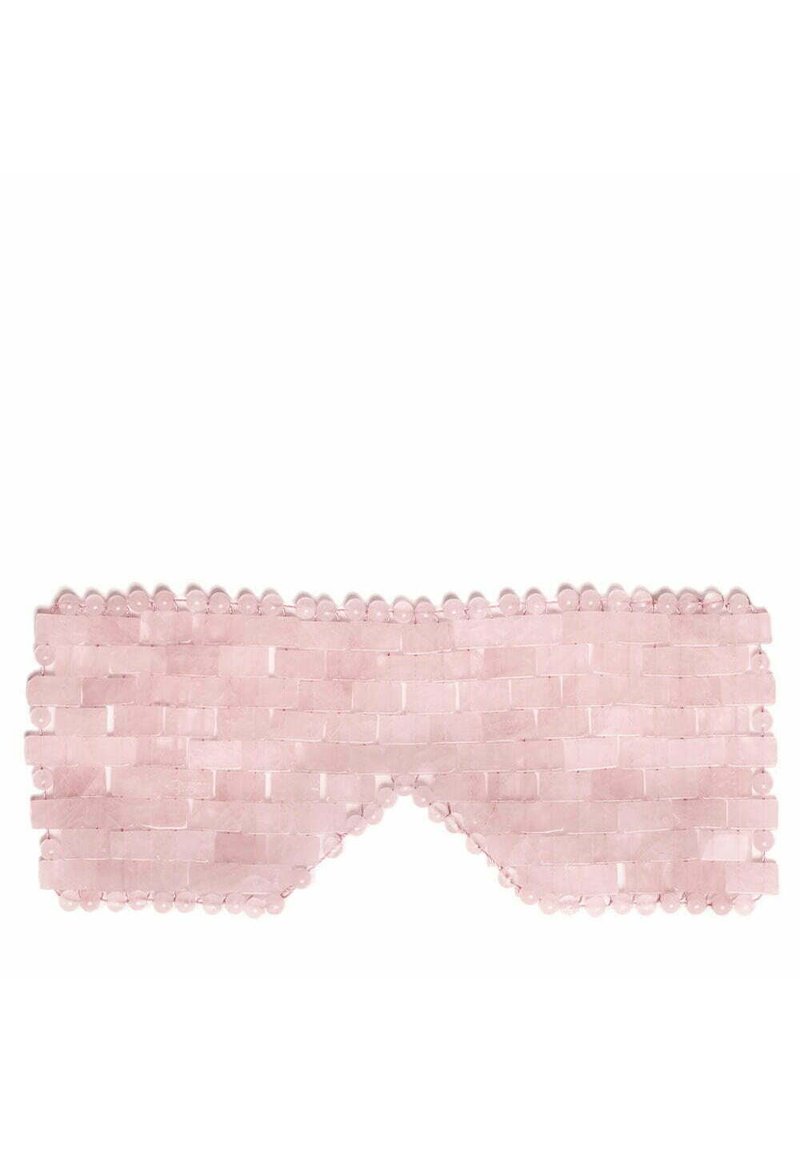 Różowa maska do spania wykonana z tkanej tkaniny o teksturowanym wzorze, z zaokrąglonymi krawędziami i koralikowymi ozdobami wzdłuż górnej krawędzi.