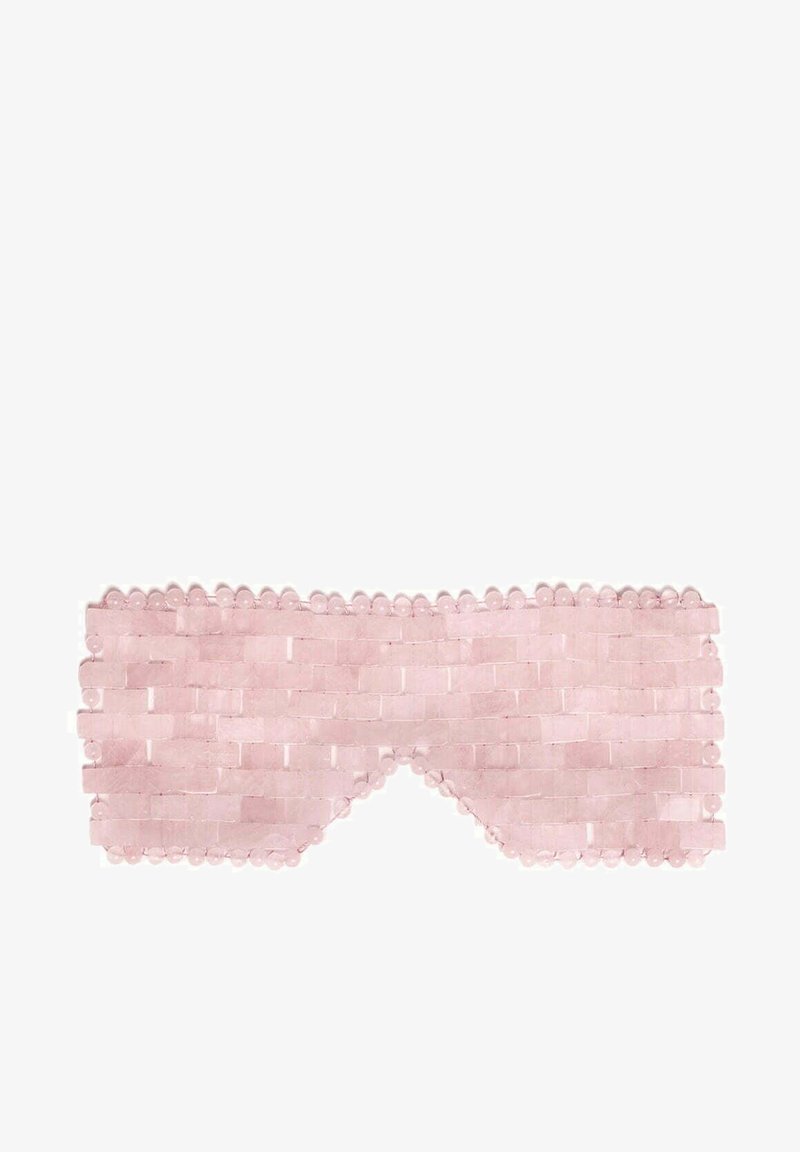 Różowa maska do spania wykonana z tkanej tkaniny o teksturowanym wzorze, z zaokrąglonymi krawędziami i koralikowymi ozdobami wzdłuż górnej krawędzi.
