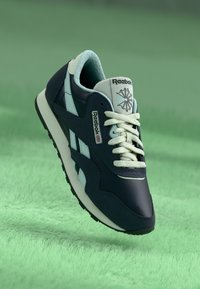 Baskets Reebok bleu marine et bleu clair avec une finition texturée, dotées d'une semelle blanche, d'un design à lacets et d'un patch logo sur la languette.