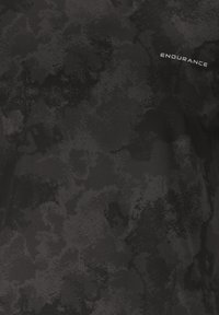 Musta urheilupaita, jossa on teksturoitu, mottleellinen kuvio. Edessä ylhäällä vasemmalla on sana "KESTÄVYYS" heijastavalla hopealla.