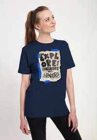 Námořnická modrá tričko s designem pomačkaného papíru a textem "PROZKOUMEJ! JEŠTĚ VÍCE DOBRODRUŽSTVÍ!" přilepeným modrým lepením.