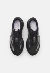 Para czarnych adidasków Adidas Adizero do biegania z szarymi paskami i sznurówkami, widziana z góry na białym tle.
