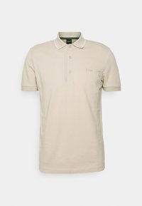 Polo shirt beige à manches courtes avec trois boutons, bordure de col blanche et petit logo "BOSS" sur la poitrine gauche.