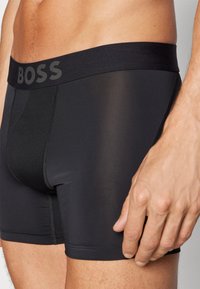 Black boxer briefs made of stretchy material with a wide waistband displaying the brand name "BOSS." Smooth texture and close fit.