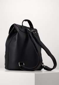 Czarny skórzany plecak o teksturowym wykończeniu. Posiada zrolowany top, regulowane paski oraz srebrne akcenty. W zestawie kieszeń na suwak z boku.
