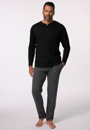 Chemise Henley noire à manches longues avec trois boutons, associée à un pantalon de loisirs gris léger. Les deux vêtements ont une coupe décontractée et une texture douce.